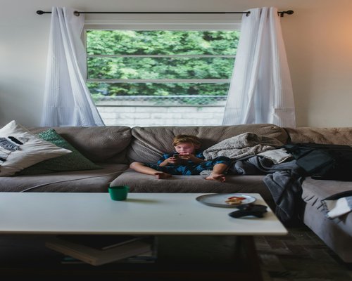 A person resting calmly on a sofa holding a cup of tea without using a phone
